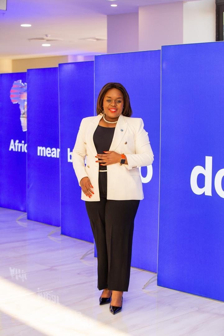 Segolame Thaga in a white blazer on a stage with blue event panels